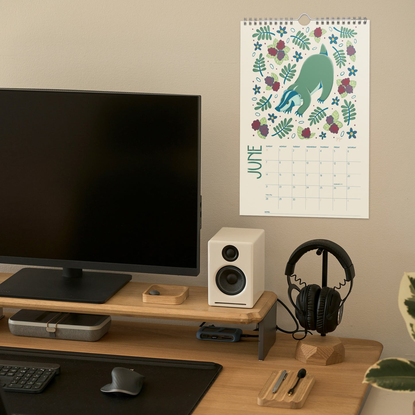 2026 wire-bound wall calendar hanging on a neutral wall, displaying colourful folk-art animal artwork and a clear monthly layout. Ideal for home offices, kitchens, studios, classrooms, or anyone looking for a decorative illustrated 2026 wall calendar with unique art.