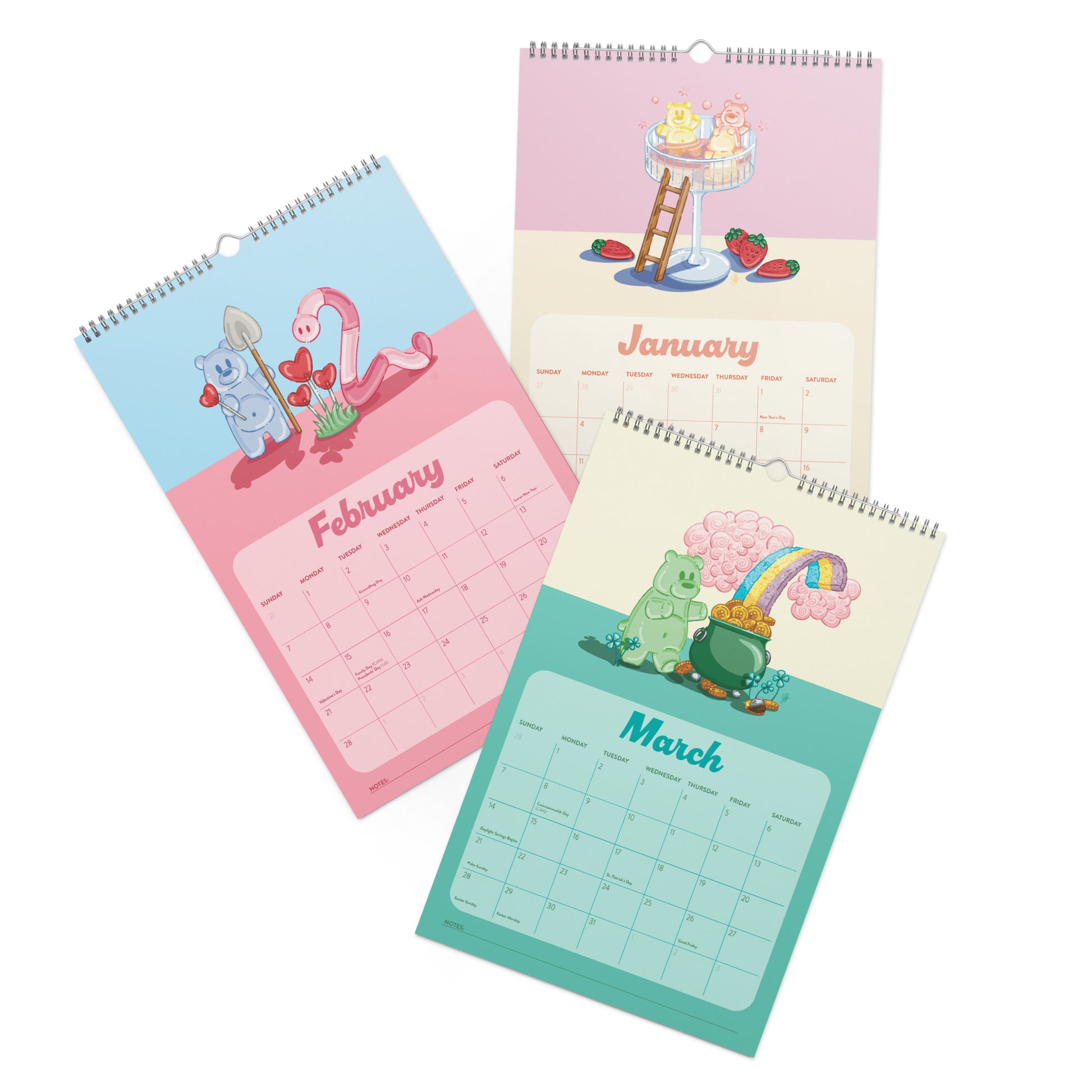 Three spiral-bound wall calendars shown overlapping on a white background, each with a different pastel illustration: January with a pink-and-yellow scene, February with a blue-and-pink scene, and March with a teal-and-yellos scene featuring gummy bears and candy illustrations