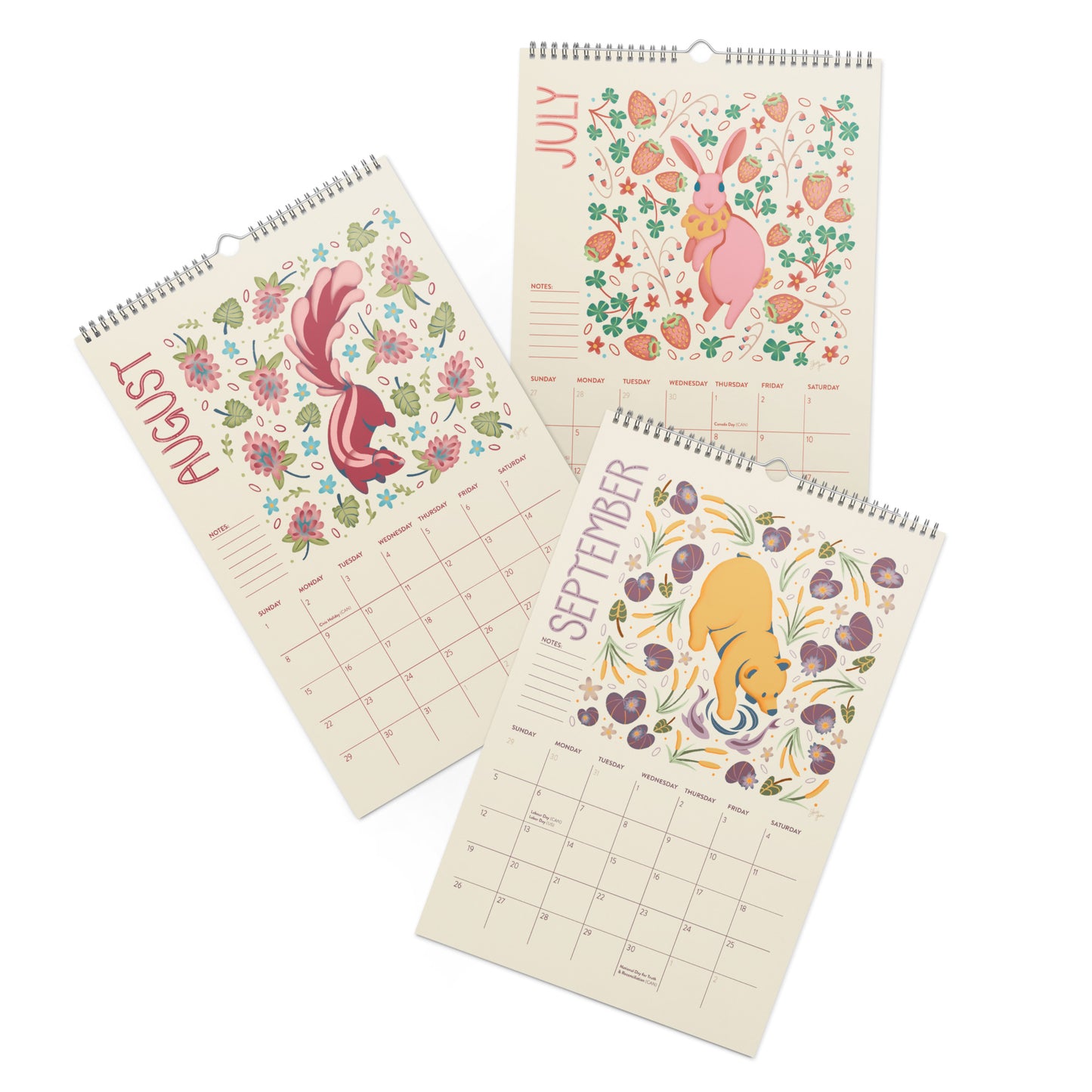 Three spiral-bound monthly calendar pages for July, August, and September, each featuring a colorful spring animal illustration on a cream background with floral details. A 2027wall calendar featuring colourful folk-art animal illustrations displayed in a flat lay. Wire-bound with premium thick paper, this illustrated monthly calendar showcases vibrant artwork for each month. Ideal for shoppers looking for a 2027 calendar, animal art calendar, home décor calendar, or unique artist-designed wall calendar.